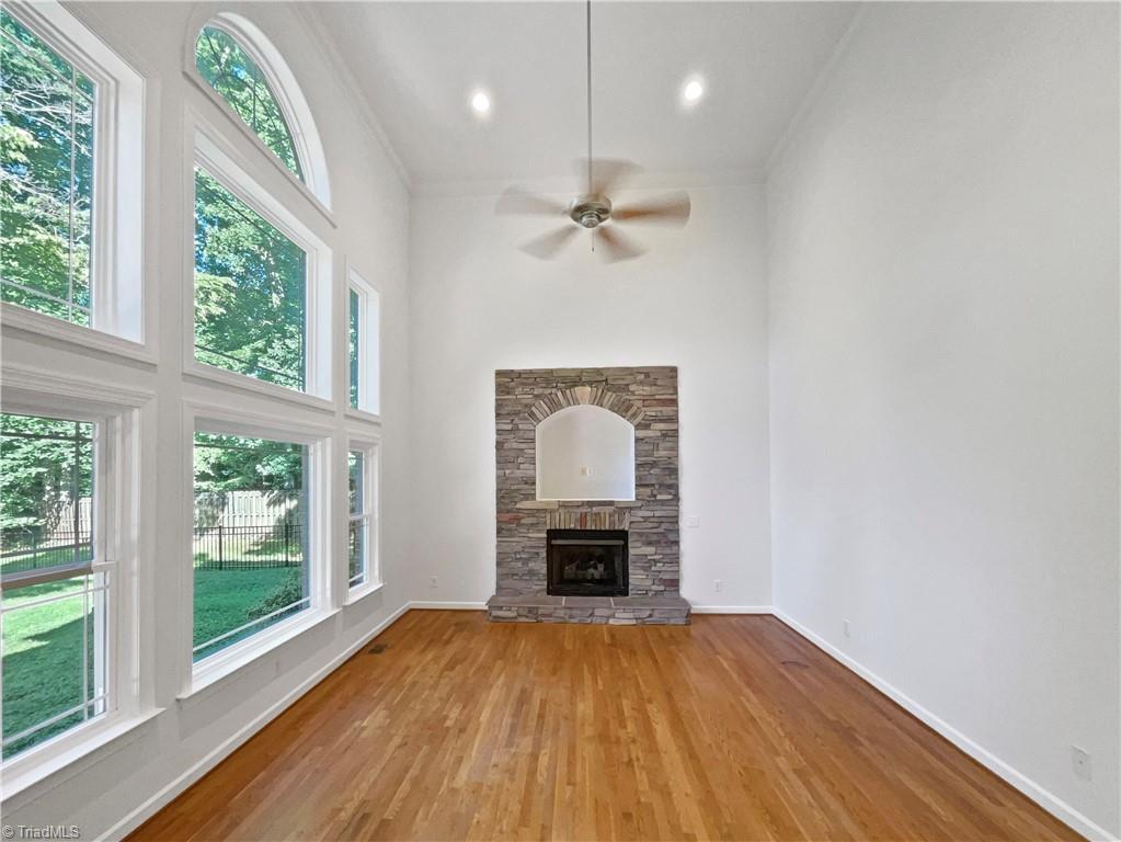 350 Bent Creek Trl, Kernersville, NC 27284 - unfurnished living room with plenty of natural light, wood finished floors, ornamental molding, a ceiling fan, and a stone fireplace