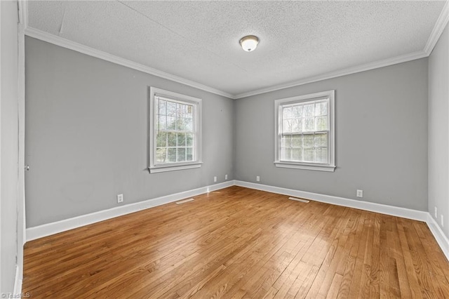 spare room featuring crown molding, visible vents, light wood-style floors, a textured ceiling, and baseboards