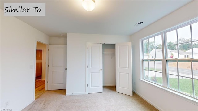 unfurnished bedroom featuring light colored carpet and a closet