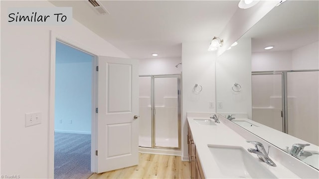 bathroom featuring a shower with door and vanity