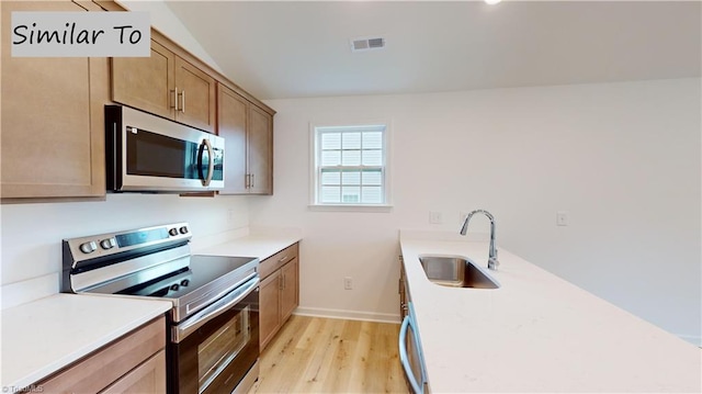 kitchen with appliances with stainless steel finishes, light hardwood / wood-style flooring, and sink