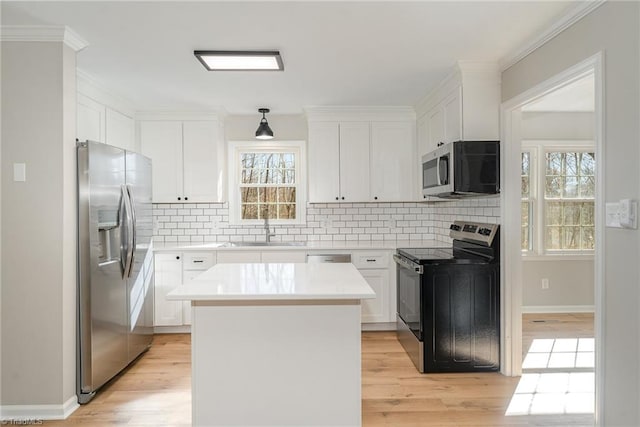 kitchen with light wood finished floors, appliances with stainless steel finishes, decorative backsplash, and a sink