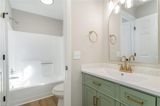 full bath featuring toilet, bathtub / shower combination, wood finished floors, and vanity