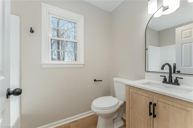 bathroom with toilet, baseboards, wood finished floors, and vanity