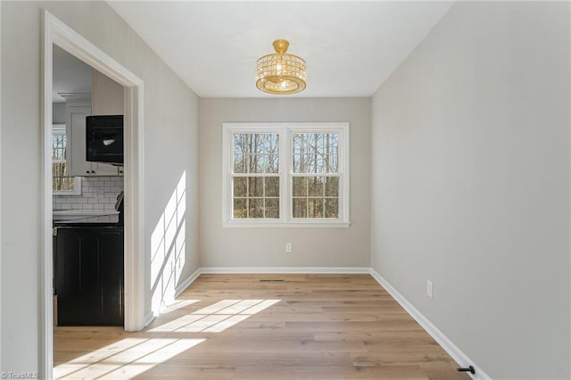 unfurnished dining area featuring baseboards and light wood-style floors