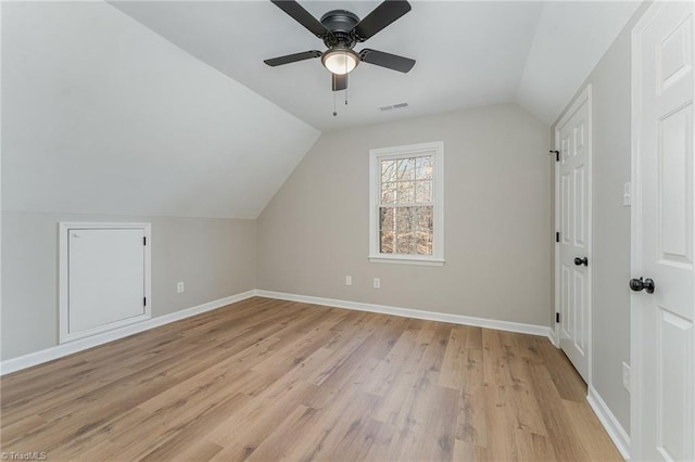 additional living space featuring visible vents, baseboards, a ceiling fan, light wood-style flooring, and vaulted ceiling