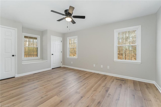 unfurnished bedroom with light wood-style floors, multiple windows, ceiling fan, and baseboards