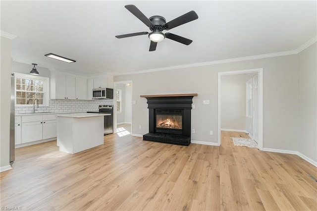 kitchen with stainless steel appliances, a kitchen island, a sink, open floor plan, and light wood-type flooring