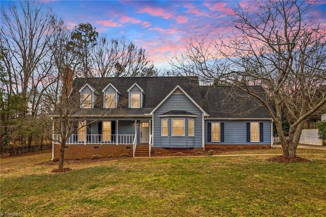 cape cod-style house with a yard and covered porch