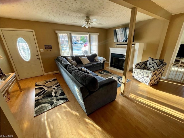 living room featuring hardwood / wood-style flooring, ceiling fan, and a textured ceiling