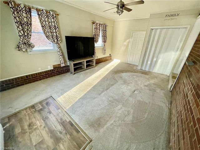 unfurnished living room with crown molding, ceiling fan, and carpet floors