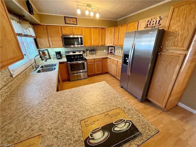 kitchen with ornamental molding, appliances with stainless steel finishes, sink, and a textured ceiling