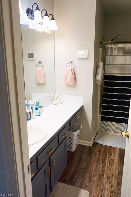 bathroom featuring curtained shower, baseboards, wood finished floors, and vanity