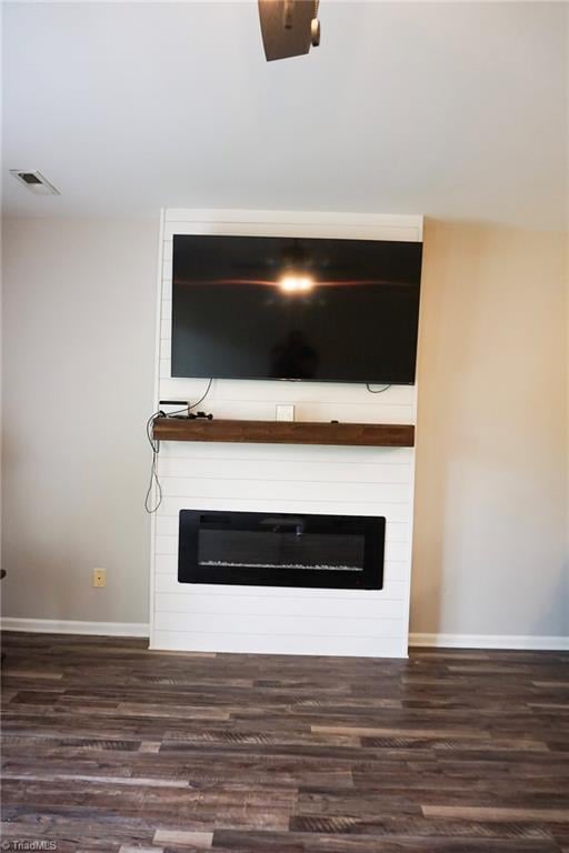 room details with a large fireplace, visible vents, wood finished floors, and baseboards