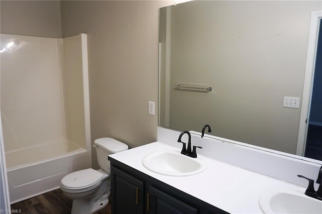 bathroom featuring a sink, double vanity, toilet, and wood finished floors
