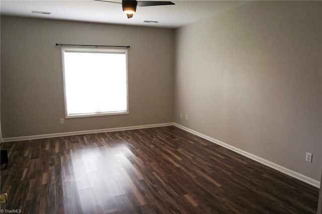 spare room featuring dark wood-style floors, baseboards, and a ceiling fan