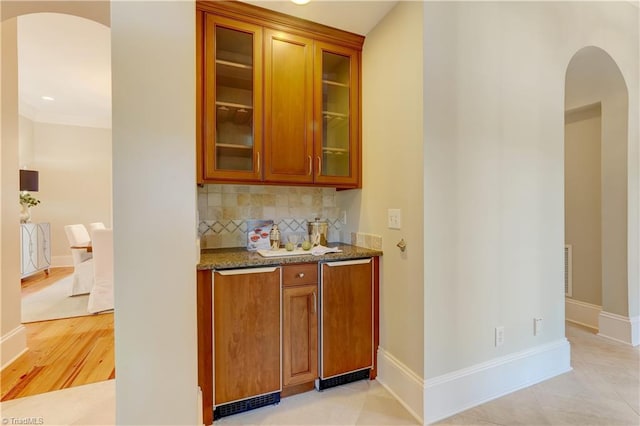 bar featuring light tile patterned flooring, light stone countertops, crown molding, and decorative backsplash