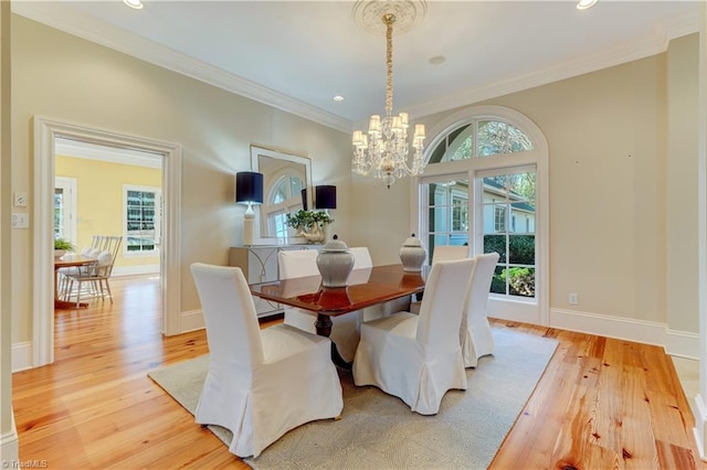 dining room with crown molding, light wood-type flooring, and a chandelier