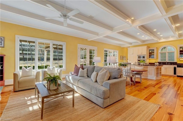 living room featuring sink, ceiling fan, french doors, beamed ceiling, and light wood-type flooring