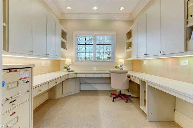 carpeted office space with crown molding and built in desk