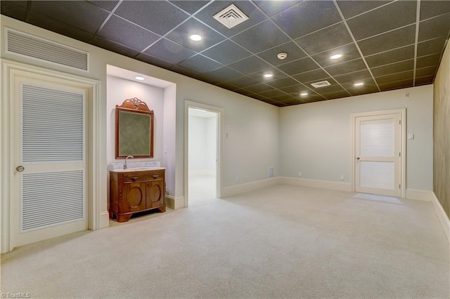 spare room featuring sink, light carpet, and a drop ceiling