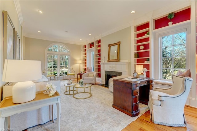 living room featuring ornamental molding, light hardwood / wood-style flooring, and built in features