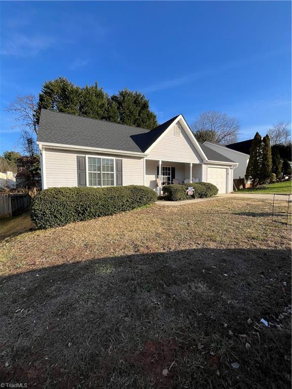 single story home featuring a garage, covered porch, and a front yard