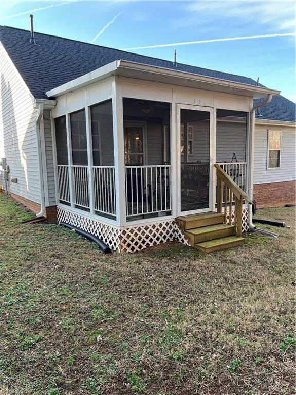 back of property with a sunroom and a lawn