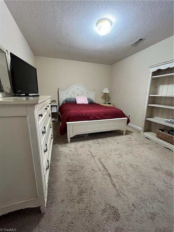 bedroom featuring dark colored carpet and a textured ceiling