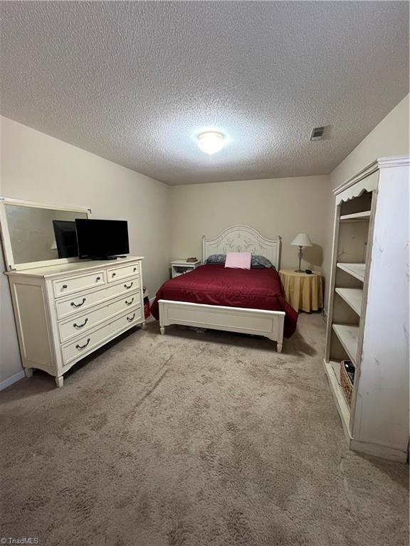 carpeted bedroom featuring lofted ceiling and a textured ceiling