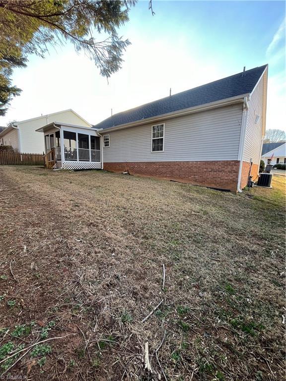 rear view of house with a sunroom, a yard, and central AC