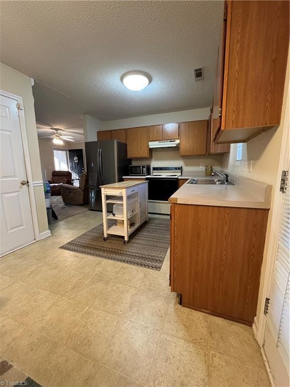 kitchen with sink, ceiling fan, range with electric cooktop, a textured ceiling, and black fridge