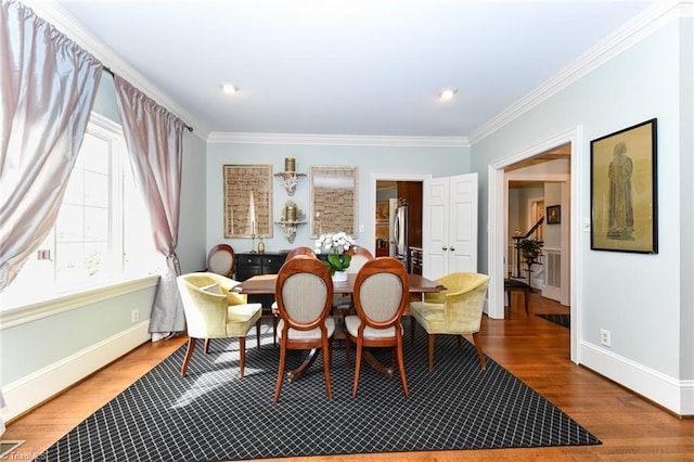 dining space featuring baseboards, wood finished floors, and crown molding