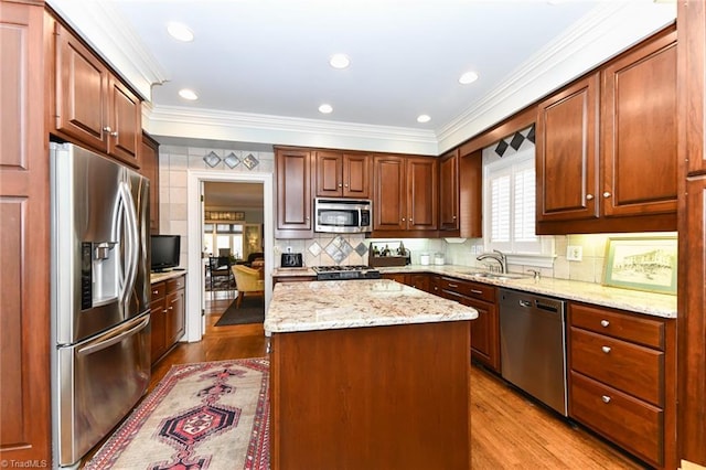 kitchen with ornamental molding, a sink, tasteful backsplash, a kitchen island, and stainless steel appliances