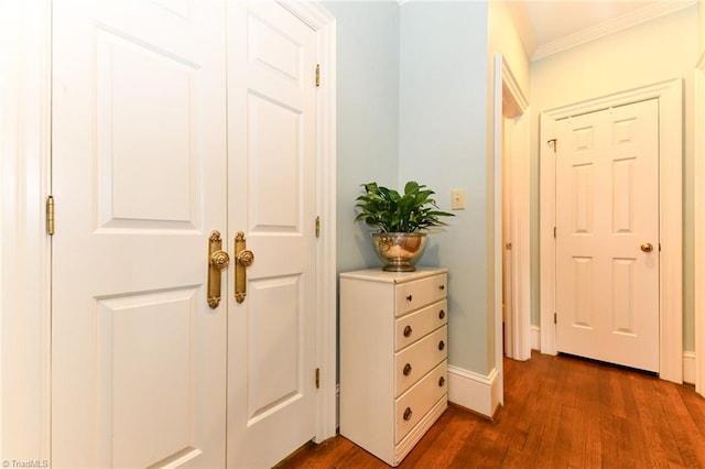 corridor with baseboards, ornamental molding, and dark wood-style flooring