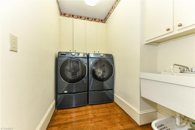 laundry room with baseboards, washer and dryer, wood finished floors, cabinet space, and a sink