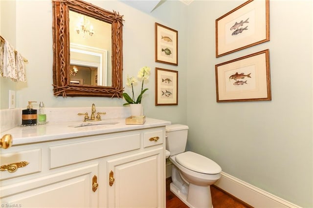 half bathroom featuring baseboards, toilet, wood finished floors, and vanity