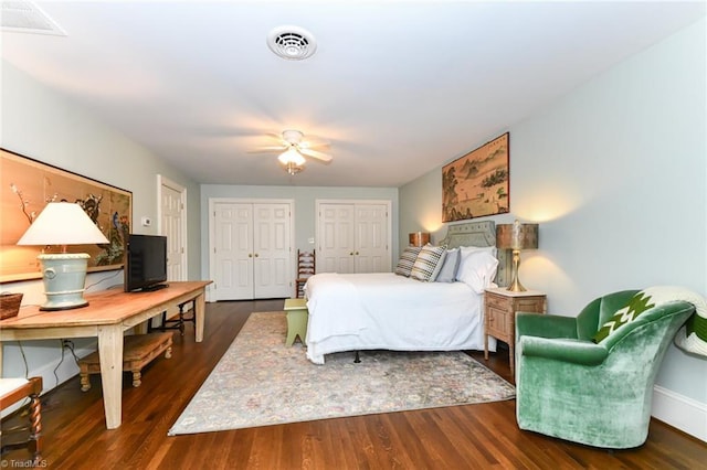 bedroom with visible vents, ceiling fan, multiple closets, and wood finished floors