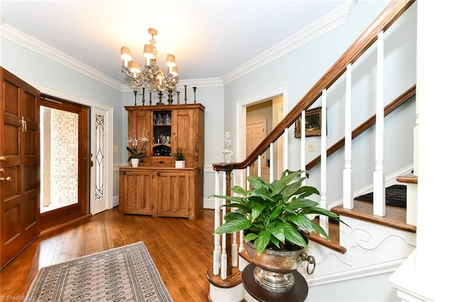 entrance foyer with a notable chandelier, stairway, crown molding, and wood finished floors