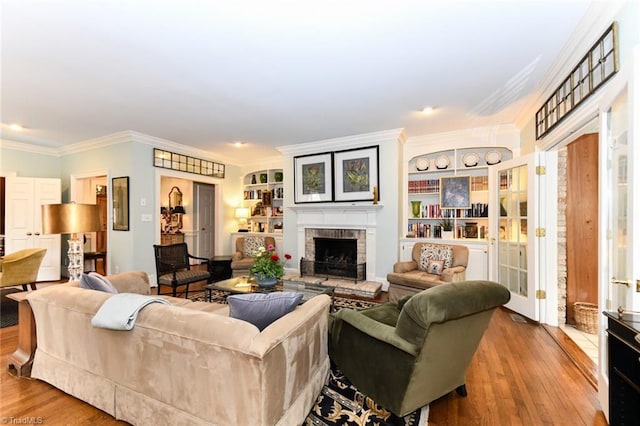 living room with wood finished floors, a fireplace, and crown molding