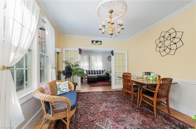 dining area featuring hardwood / wood-style flooring, crown molding, a healthy amount of sunlight, and an inviting chandelier