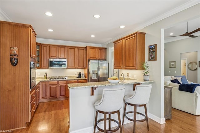 3741 Canter Dr, Trinity, NC 27370 - kitchen with appliances with stainless steel finishes, a peninsula, light wood-style floors, light stone counters, and brown cabinets