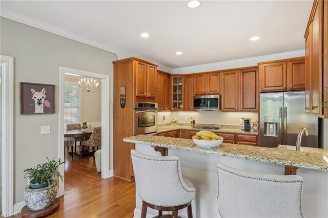 3741 Canter Dr, Trinity, NC 27370 - kitchen featuring appliances with stainless steel finishes, a breakfast bar, light stone countertops, brown cabinets, and glass insert cabinets