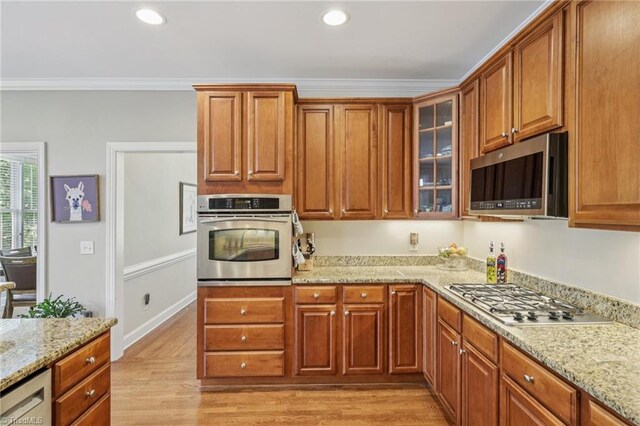 3741 Canter Dr, Trinity, NC 27370 - kitchen featuring appliances with stainless steel finishes, light wood-style floors, glass insert cabinets, light stone counters, and ornamental molding