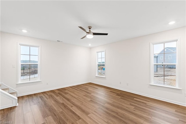 unfurnished room with a wealth of natural light, baseboards, wood finished floors, and ceiling fan