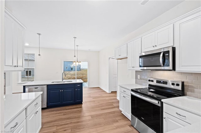 kitchen with a sink, blue cabinets, white cabinetry, and stainless steel appliances