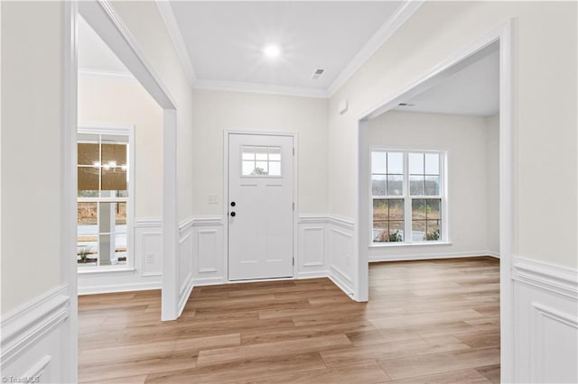 foyer featuring crown molding, plenty of natural light, visible vents, and light wood finished floors