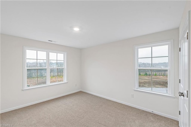 carpeted spare room featuring baseboards and visible vents