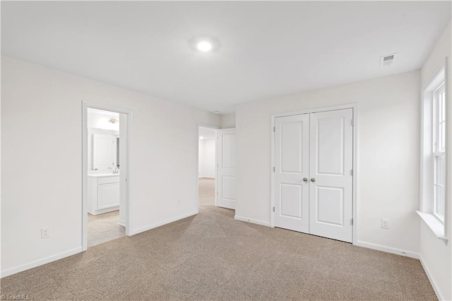 unfurnished bedroom with visible vents, baseboards, carpet, and a closet