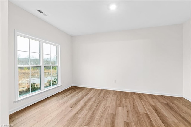 empty room featuring visible vents, light wood-style flooring, and baseboards